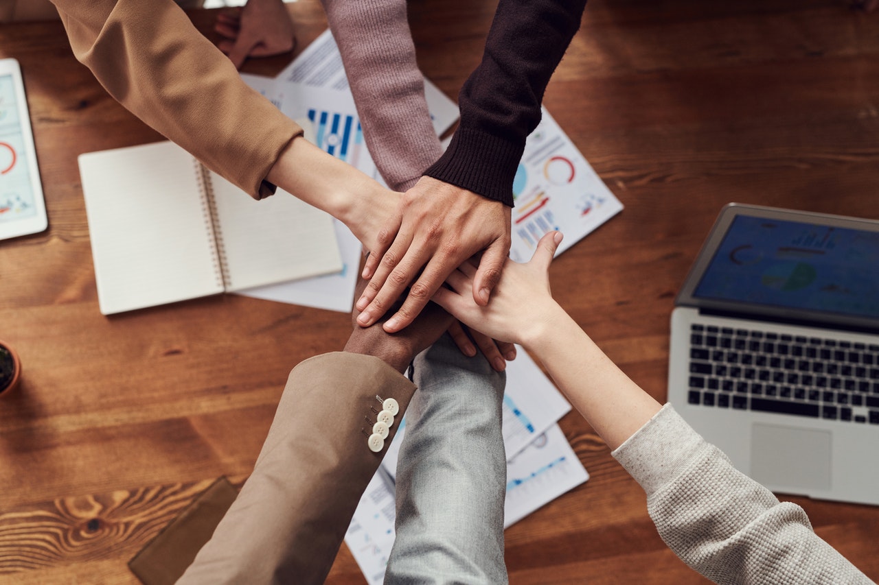 Co-Workers placing their hands together in the center on top of a desk